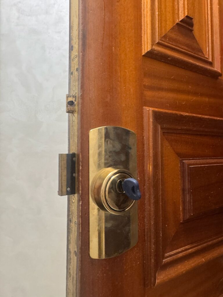 Bombín de seguridad con llave azul en puerta madera